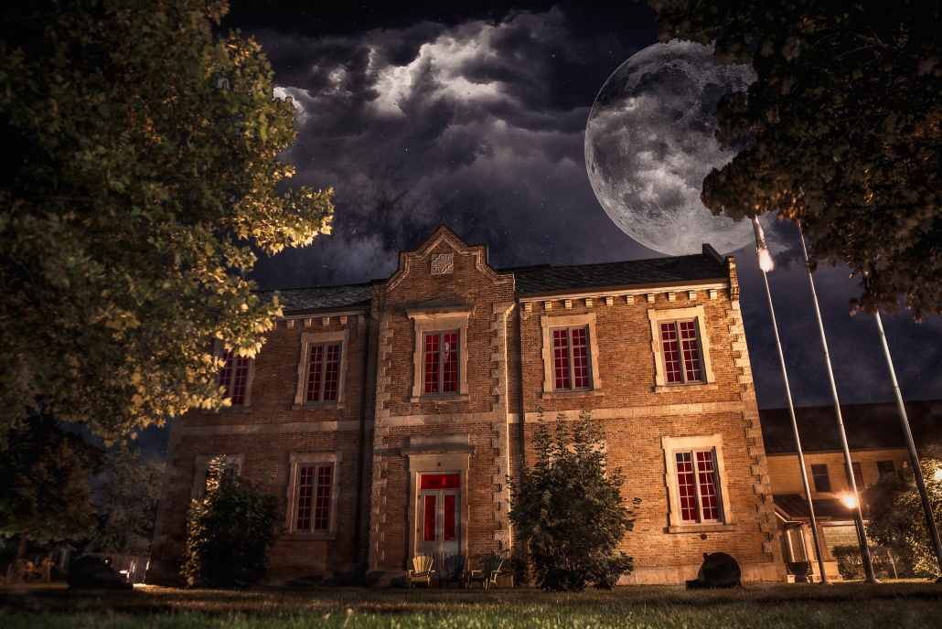 Image of Huron County Museum at night, with enlarged full moon behind the brick school house building.