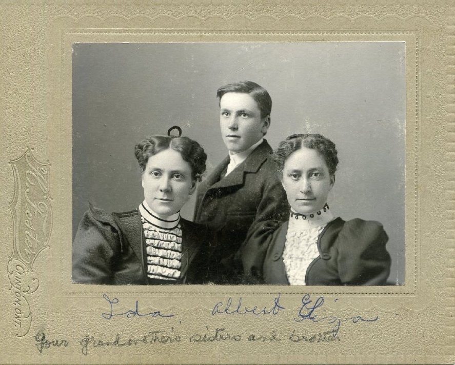 Photograph of two young women and one young man. Handwritten caption at bottom.