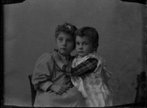 Black & white negative image of two children embracing.