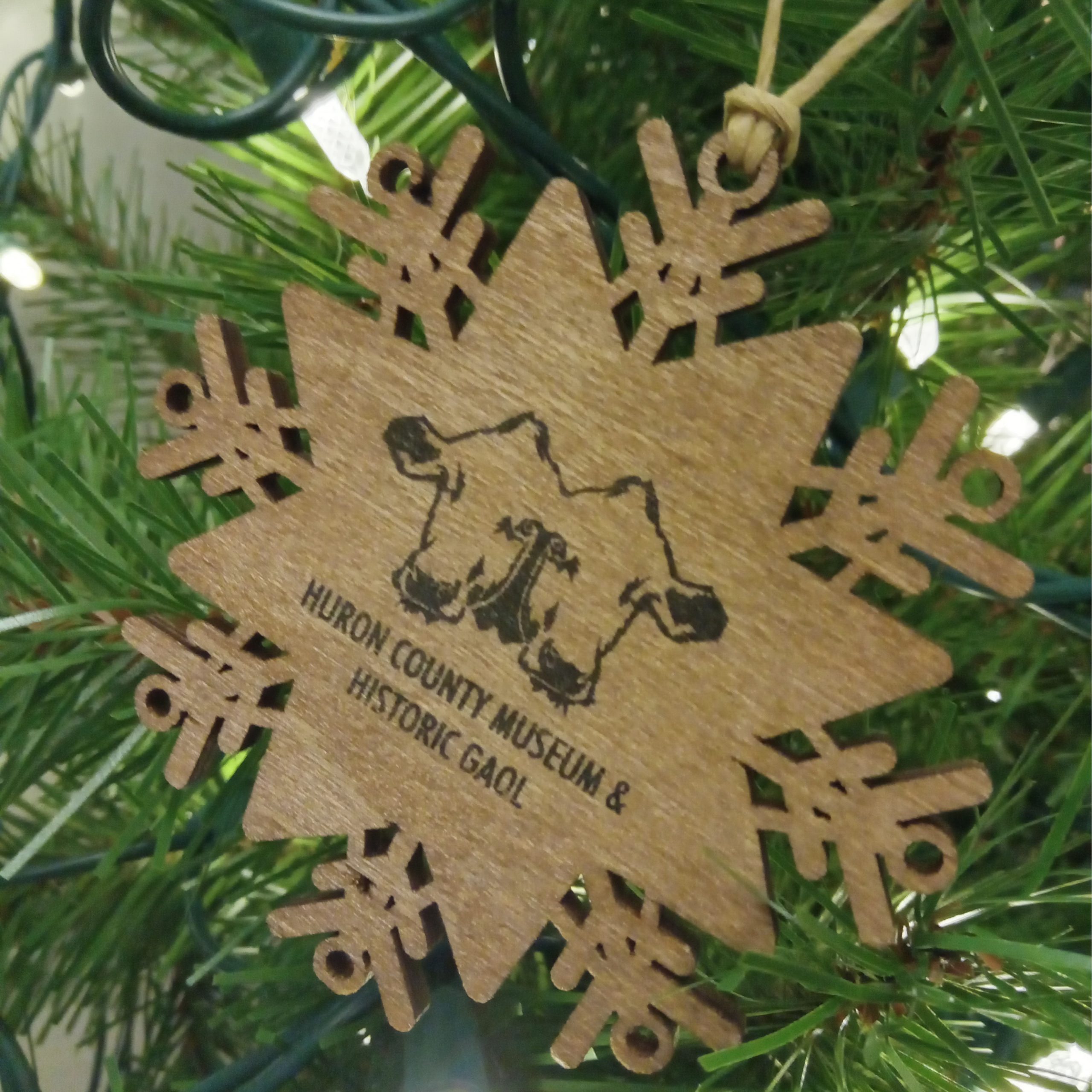 Wooden ornament in the shape of a snowflake with an illustration of the Museum's two-headed calf on the front.