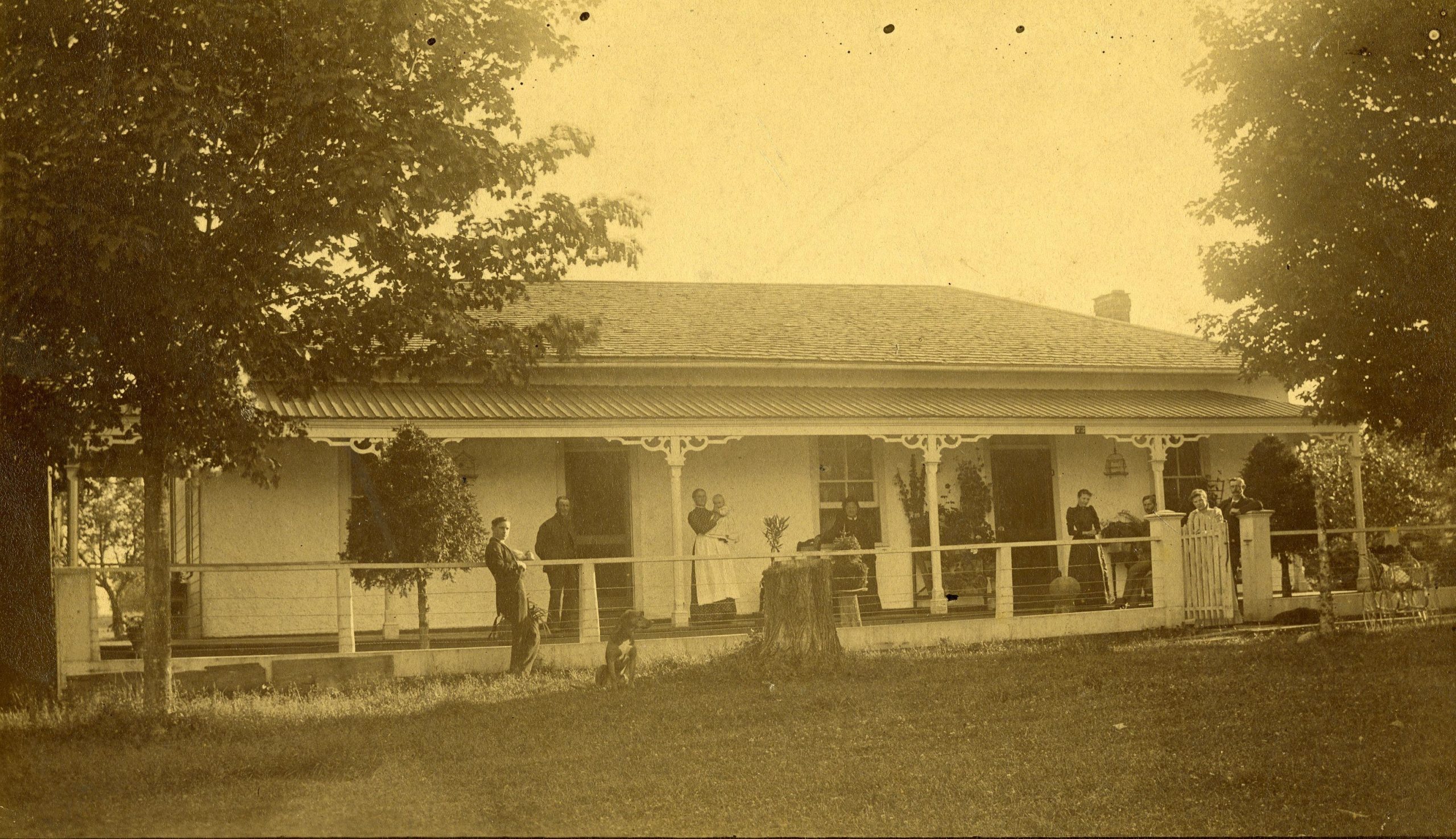 Historic image of the Ballatyne home on the bank of the Maitland River. There are a number of people standing on a wide front porch.