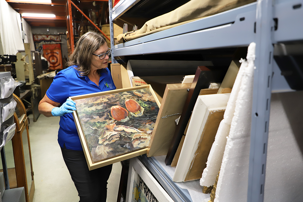 Image of Patti Lamb, Museum Registrar, looking at art work in Museum storage