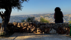 Filmmaker b. h. Yael, standing in silhouette from behind, looking out over view of Jerusalem from above.