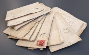Envelopes fanned out on a grey surface. Some have stamps and visible postage marks.