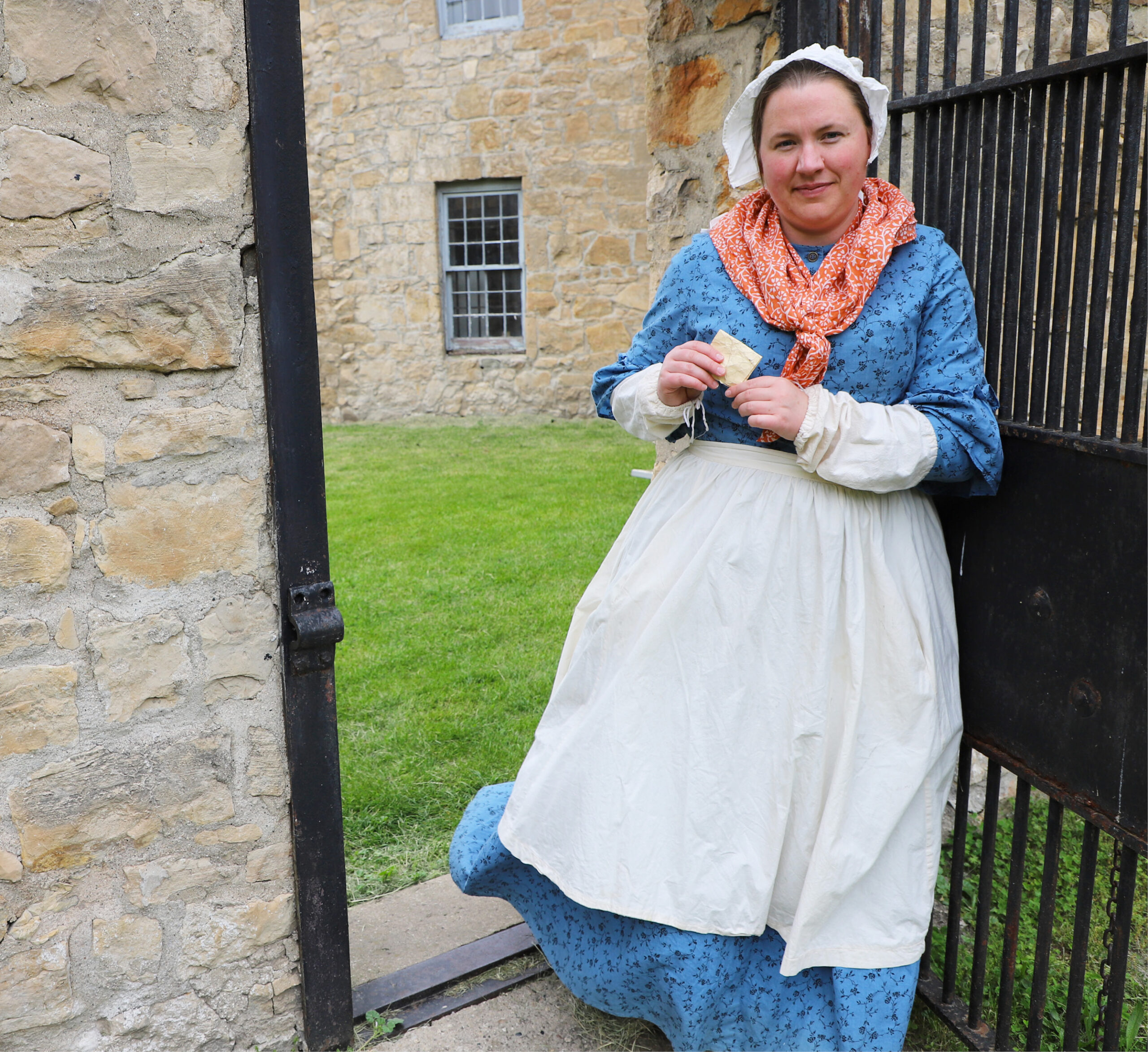 Female volunteer actor dressed in period clothing standing in the courtyard of the Gaol